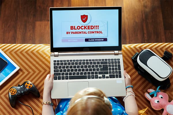 girl-in-blue-dress-sitting-on-couch-in-the-modern-living-room-having-access-restriction-by-parental-control-on-a-laptop-screen.